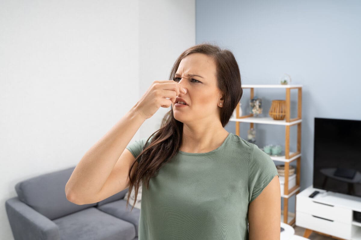 Women pluggin nose from mold smell